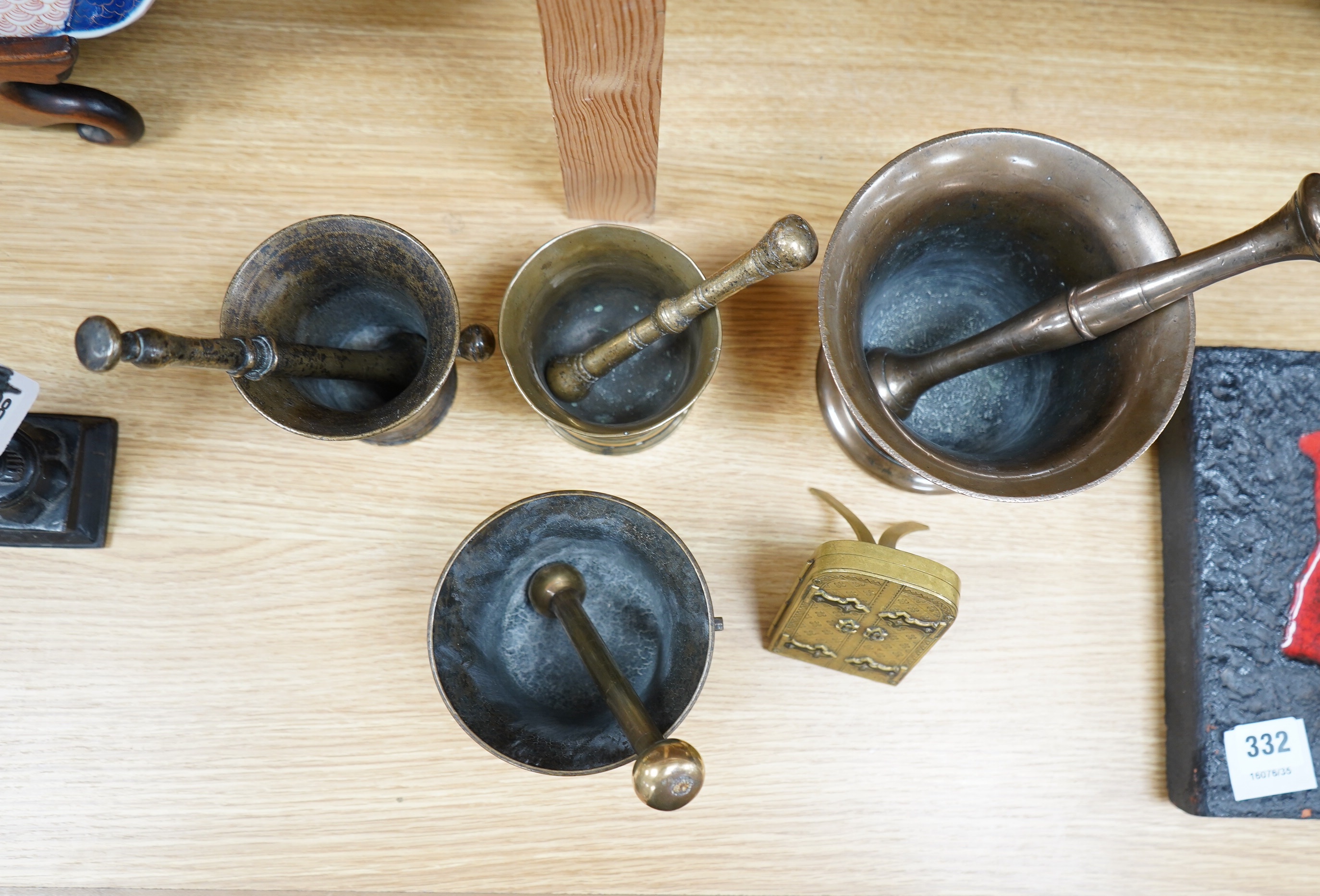 Four various bronze pestles and mortars and a small enamelled brass photograph frame, largest mortar 13cm high. Condition - fair